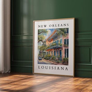 May include: A watercolor painting of a street scene in New Orleans, Louisiana. The painting features colorful buildings with balconies and lush greenery. The text "NEW ORLEANS" and "LOUISIANA" is printed at the top and bottom of the painting.