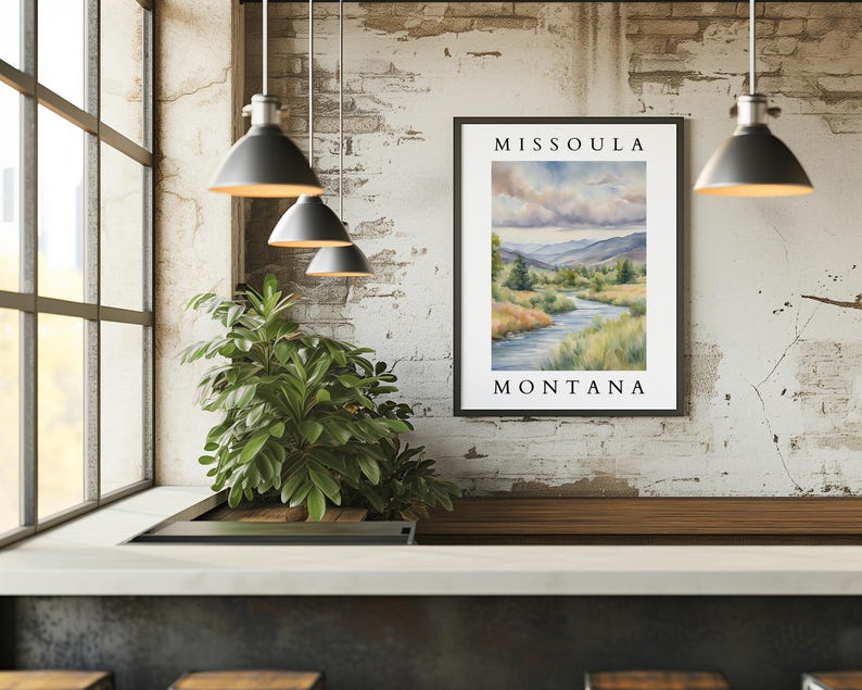 May include: A framed watercolor painting of a river scene with the text "Missoula Montana" at the top and bottom. The painting depicts a river winding through a green valley with mountains in the background.