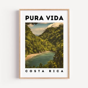 May include: A framed print featuring a scenic view of a Costa Rican beach. The image displays lush green mountains surrounding a turquoise bay. The words "PURA VIDA" and "COSTA RICA" are printed in black, bold font.