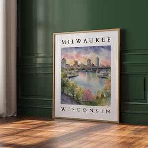 A large Milwaukee, Wisconsin watercolor print leaning against a rich green accent wall, with soft natural lighting highlighting the artwork.