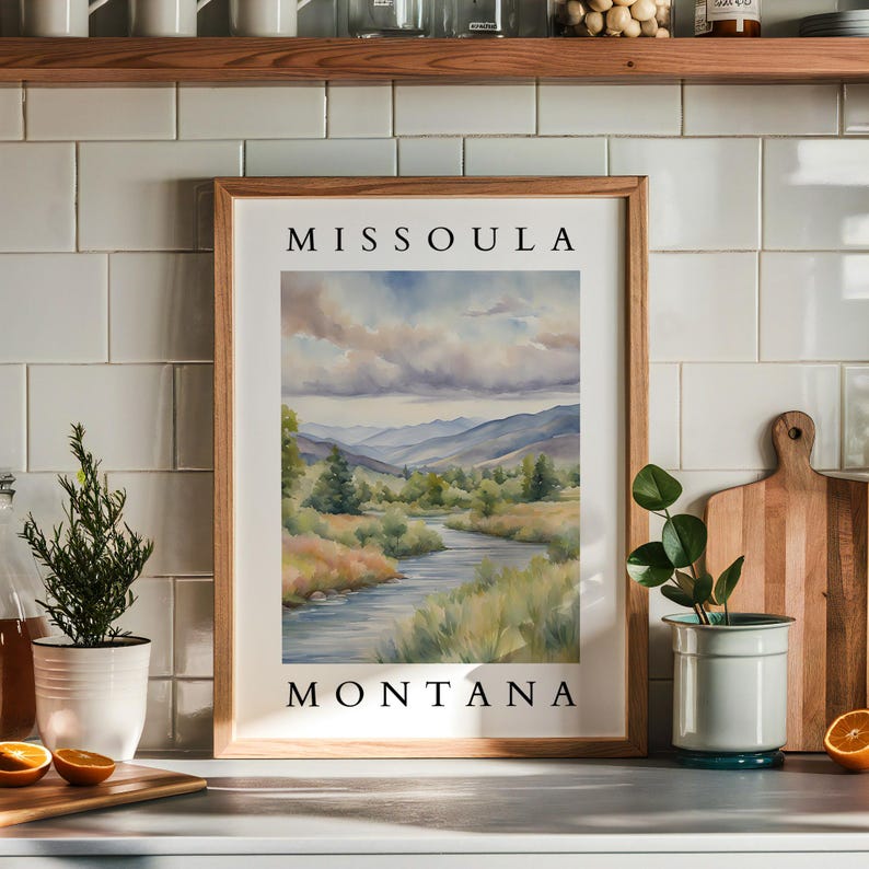 May include: A framed watercolor painting of a river winding through a valley with mountains in the background. The painting is titled "Missoula, Montana".