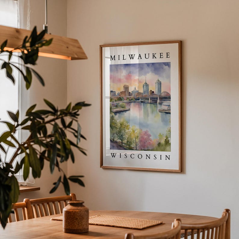 A Milwaukee cityscape print framed and hanging on a beige wall in a cozy dining area, surrounded by wooden furniture and soft indoor lighting.