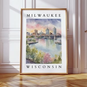 A large Milwaukee cityscape print hanging in a bright, elegant space with white paneled walls, a cozy seating area, and large windows letting in natural light.