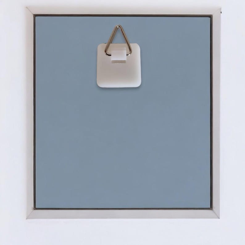 May include: A white plastic picture hanger with a silver metal hook. The hanger is attached to a light blue wall.