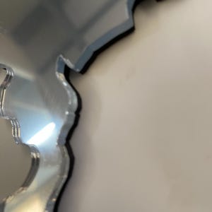 May include: A silver mirror in the shape of a state or country. The mirror is slightly distorted, giving it a unique look.