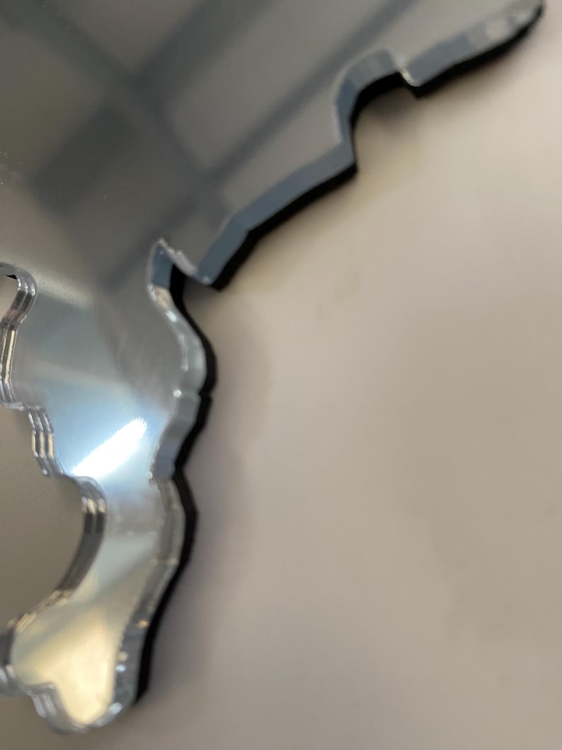 May include: A silver mirror in the shape of a state or country. The mirror is slightly distorted, giving it a unique look.