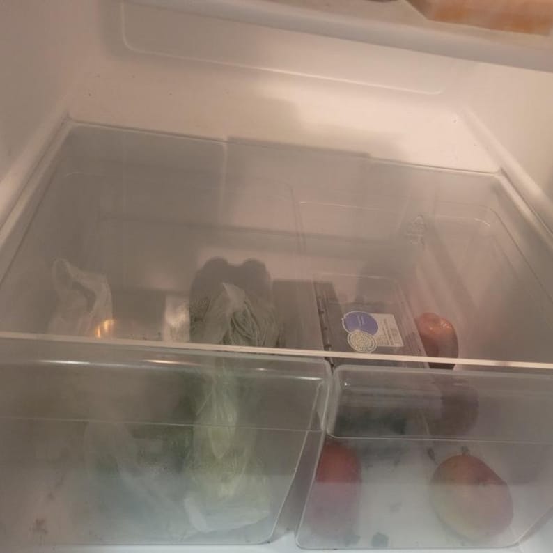 May include: An open refrigerator with two clear plastic drawers. The top drawer contains a plastic bag of leafy greens, a plastic container of blueberries, and a red apple. The bottom drawer contains a plastic bag of leafy greens and a red apple.