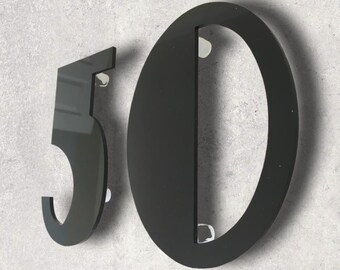 May include: Black house numbers, 50, made of acrylic. The numbers are mounted on a wall.
