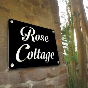 Könnte beinhalten: Schwarzes Schild mit weißer Aufschrift "Rose Cottage".