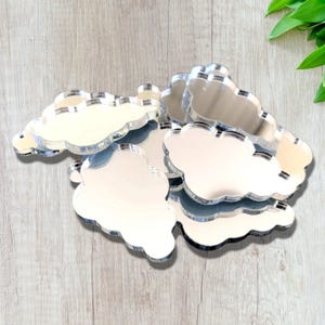 May include: A set of six silver mirrored cloud shapes. The clouds are all different sizes and shapes, and they are arranged in a pile.