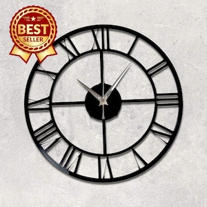 Puede incluir: Un reloj de pared circular grande de color negro con un diseño de marco abierto y números romanos prominentes. El reloj tiene un centro circular negro con manecillas finas de color plateado. Se observa una insignia roja y dorada de BEST SELLER.