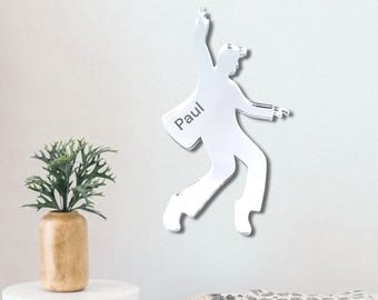 May include: A silver mirror wall decor featuring a silhouette of a person dancing with the name "Paul" engraved on the figure.