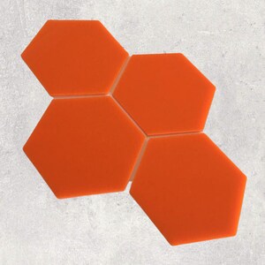 Puede incluir: Cuatro azulejos hexagonales de color naranja dispuestos en un patrón escalonado. Los azulejos están hechos de un material liso y brillante.