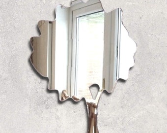 Peut inclure: Un miroir en forme d'arbre argenté avec une canopée arrondie et un seul tronc. Le miroir reflète une image floue d'une porte.