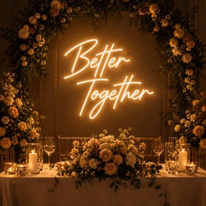K&ouml;nnte beinhalten: Eine Hochzeitsfeier mit einem Neon-Schild mit der Aufschrift "Better Together". Das Schild strahlt ein warmes Licht aus. Die Szene ist mit Blumenarrangements, Kerzen und Weingl&auml;sern geschm&uuml;ckt und schafft eine romantische Atmosph&auml;re.