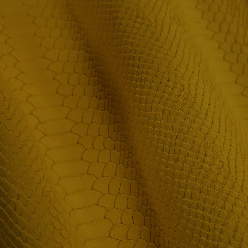Peut inclure: Gros plan sur un tissu textur&eacute; jaune avec un motif peau de crocodile.