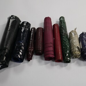 May include: Assortment of rolled leather pieces in various colours and textures, including black, blue, red, green, and beige.