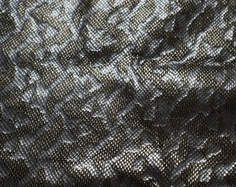 May include: Close-up of a silver fabric with a textured, snake-like pattern.