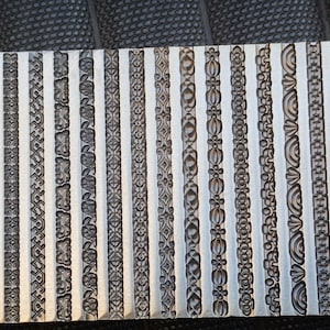 May include: A metal plate featuring 24 distinct embossed designs, each showcasing a unique border pattern. The plate is silver in colour and has a smooth, polished finish.