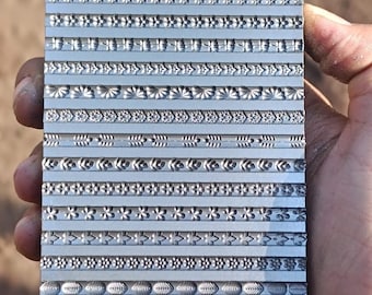 Könnte beinhalten: Eine Metallplatte mit verschiedenen dekorativen Mustern, die in ihre Oberfläche geprägt sind. Die Platte wird in einer Hand gehalten.