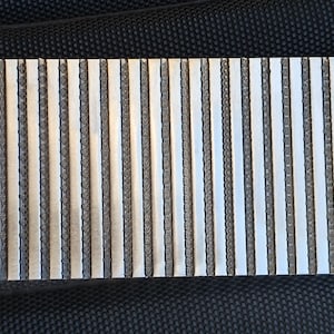 May include: A silver metal panel with a series of vertical lines, creating a textured surface.