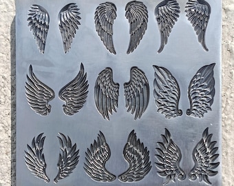 May include: A metal mold with various wing designs. The wings are in pairs and feature detailed feather patterns. The mold is a square shape and has a silver color.