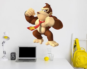 Può includere: Un personaggio di Donkey Kong marrone e beige che indossa una cravatta rossa con le lettere DK. Il personaggio è in una posa di combattimento con entrambi i pugni serrati.