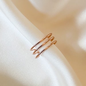 Könnte beinhalten: Ein Ring aus Roségold mit drei übereinander gestapelten Bändern.