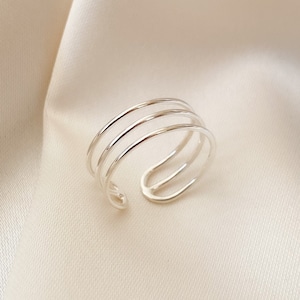 Op de afbeelding: Een zilveren ring met drie banden, ontworpen om aan de vinger te dragen.