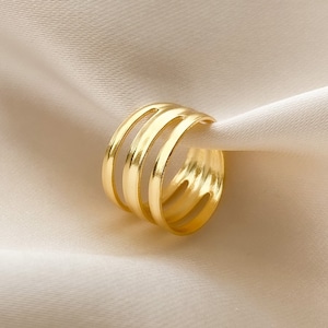 May include: Gold ring with a layered design. The ring is made of multiple bands that are stacked on top of each other.
