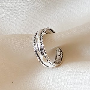 Peut inclure: Une bague ajustable en argent avec une bande texturée.