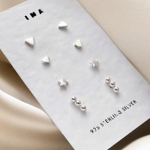 May include: A set of six sterling silver earrings on a white card. The earrings are in the shapes of a heart, star, triangle, and three small balls.