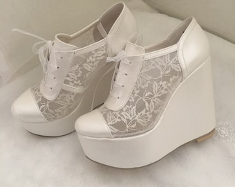 Può includere: Scarpe con plateau a zeppa bianche in pizzo con punta in raso. Le scarpe hanno una chiusura con lacci sul davanti e una suola platform spessa.