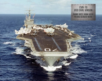 Puede incluir: Un portaaviones gris, el USS Carl Vinson (CVN-70), está en el mar. El barco tiene una gran cubierta de vuelo con varios aviones estacionados en él. El nombre y el número del barco son visibles en el costado del barco.
