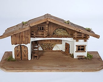 May include: A wooden nativity scene with a brown roof and white walls. The scene features a stable with a hayloft, a ladder, and a small window. The stable is set on a wooden base.