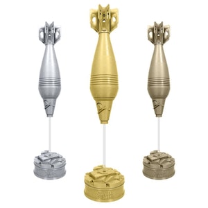 May include: Three decorative mortar-shaped objects in silver, gold, and bronze. Each is mounted on a white stem and a textured base with engraved text. The objects have detailed designs and are set against a white background.