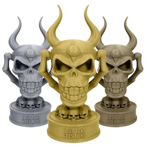 Può includere: Tre trofei a forma di teschio in oro, grigio e marrone. Ogni trofeo ha grandi corna, una faccia di teschio e una base con la scritta "YOUR TEXT GOES HERE". I trofei sono probabilmente a tema fantasy o gaming.