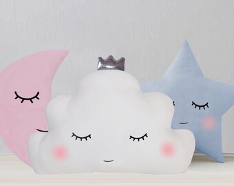 May include: Three plush pillows shaped like a cloud, a crescent moon, and a star. The cloud pillow has a crown on top and all three pillows have embroidered eyes and blushing cheeks.