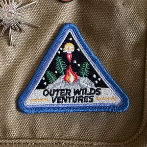 Pode incluir: Uma caneca de cerâmica branca com uma alça preta e o texto "But First, Coffee" em preto, com uma fonte manuscrita. A caneca está sobre uma superfície branca.