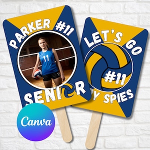 Könnte beinhalten: Zwei blaue und goldene Schilder zum Thema Volleyball mit einem Foto einer Volleyballspielerin auf einem Schild. Das Schild links lautet "Parker #11 Senior" und das Schild rechts "Let's Go #11 By Spies".