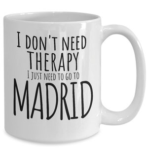 K&ouml;nnte beinhalten: Wei&szlig;e Keramik-Kaffeetasse mit schwarzem Text, der "Ich brauche keine Therapie, ich muss nur nach Madrid" lautet.