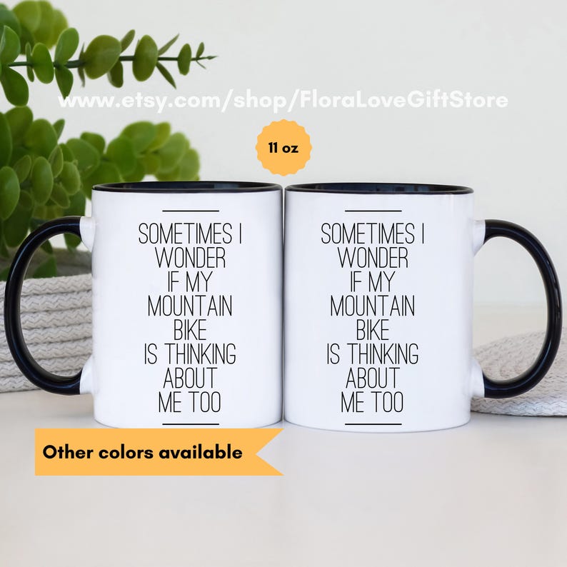 May include: Two white ceramic mugs with black rims and handles. The mugs are 11 ounces and feature the text "Sometimes I wonder if my mountain bike is thinking about me too".