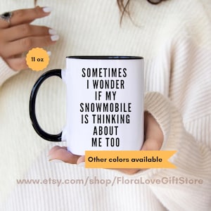 May include: White ceramic mug with a black rim and handle. The mug has black text that reads "Sometimes I wonder if my snowmobile is thinking about me too". The mug is 11 ounces.