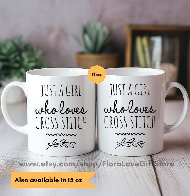 May include: Two white ceramic mugs with black text that reads "Just a girl who loves cross stitch" and a small floral design. The mugs are 11 ounces and are available in 15 ounces.