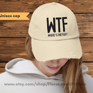 May include: A beige unisex baseball cap with distressed fabric and black embroidered text that reads "WTF Where's the Fish?"