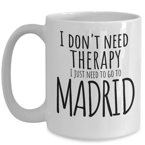 K&ouml;nnte beinhalten: Wei&szlig;e Keramik-Kaffeetasse mit schwarzem Text, der "Ich brauche keine Therapie, ich muss nur nach Madrid" lautet.