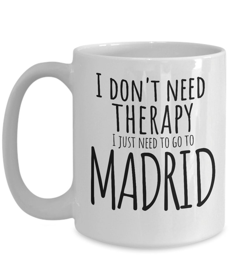 K&ouml;nnte beinhalten: Wei&szlig;e Keramik-Kaffeetasse mit schwarzem Text, der "Ich brauche keine Therapie, ich muss nur nach Madrid" lautet.