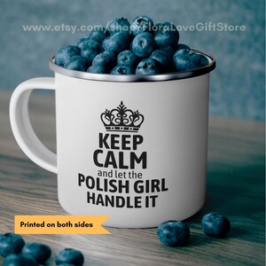 May include: White enamel mug with a silver rim, filled with blueberries. The mug features the text "KEEP CALM and let the POLISH GIRL HANDLE IT" in black, with a crown graphic above. The words "Printed on both sides" are also visible.