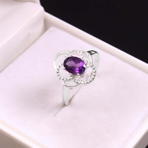 May include: A silver ring with a purple amethyst gemstone set in a delicate floral design.