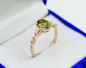 May include: A gold ring featuring a green oval gemstone and small clear gemstones set in a delicate design.